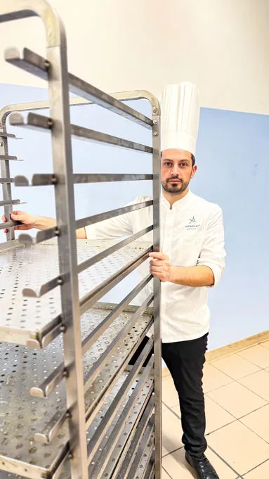Baker with a steel rack holding dough trays